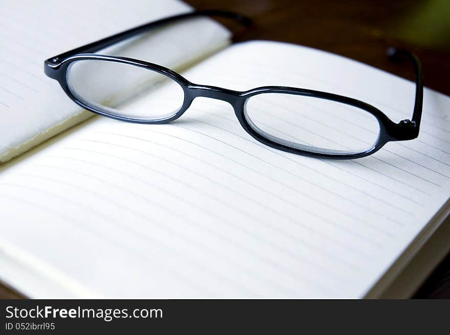 Eyeglasses put on blank notebook. Eyeglasses put on blank notebook