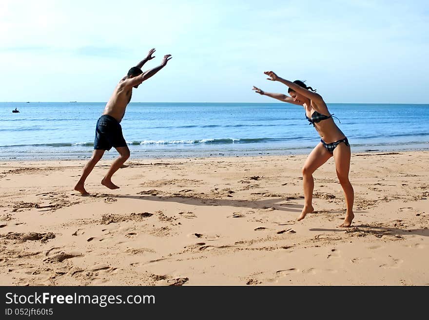 A young men and women doing cartwheels on the beach