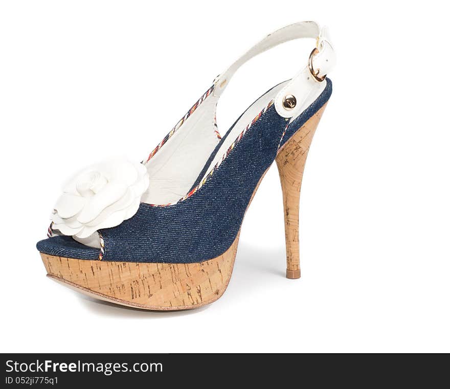 Stylish modern blue high-heeled ladies shoe with a textile texture, white rose decoration, cork platform soles and a sling back on a white studio background. Stylish modern blue high-heeled ladies shoe with a textile texture, white rose decoration, cork platform soles and a sling back on a white studio background