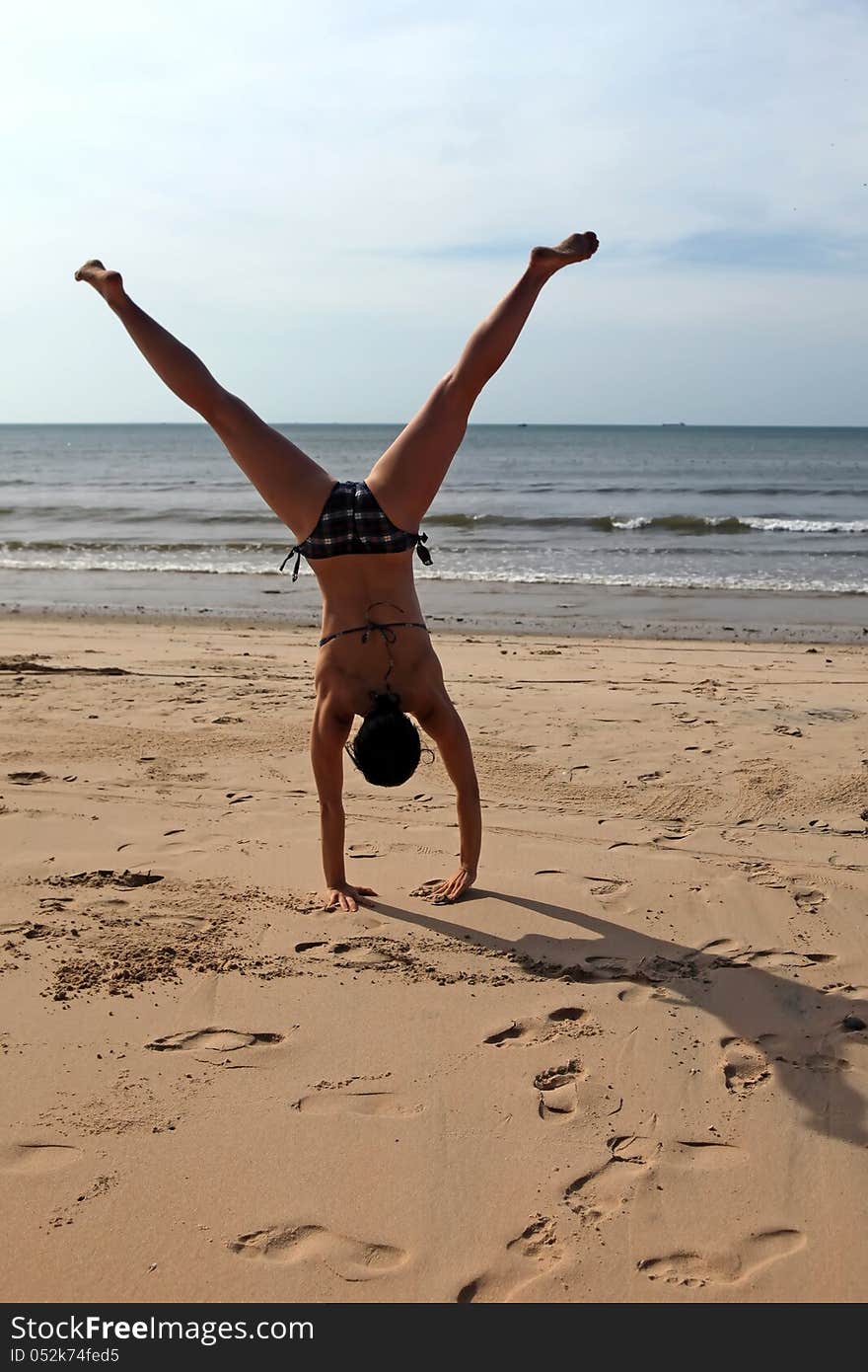 A young woman doing cartwheels on the beach