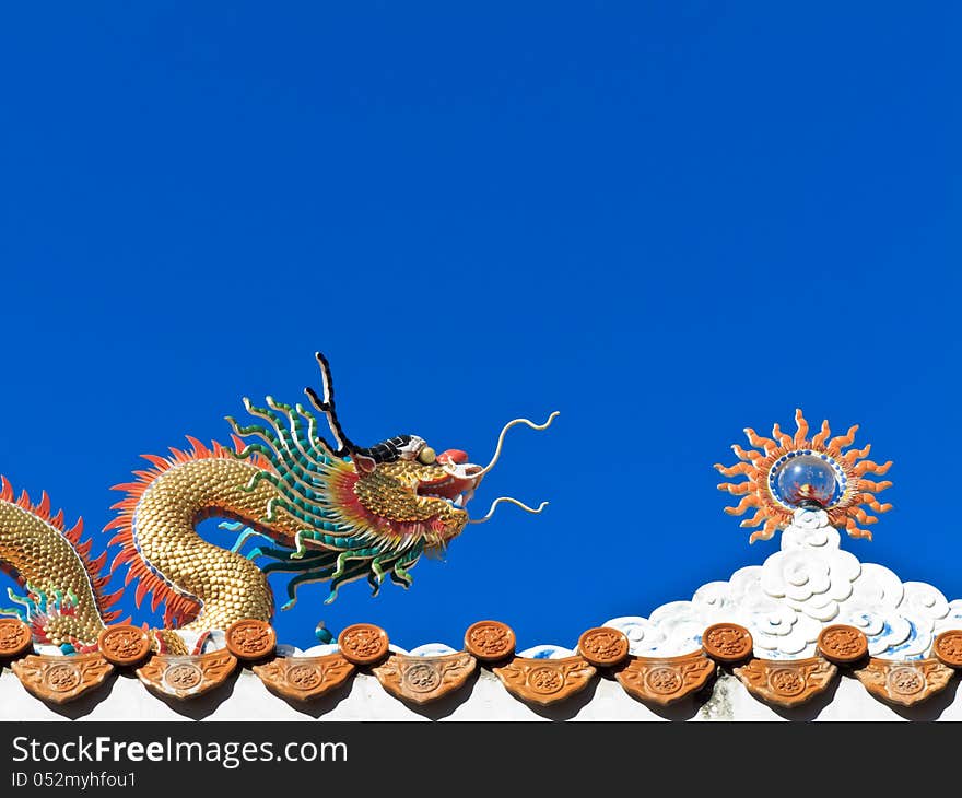 Chinese Dragon and sun sculpture on the temple roof with blue sky background. Chinese Dragon and sun sculpture on the temple roof with blue sky background