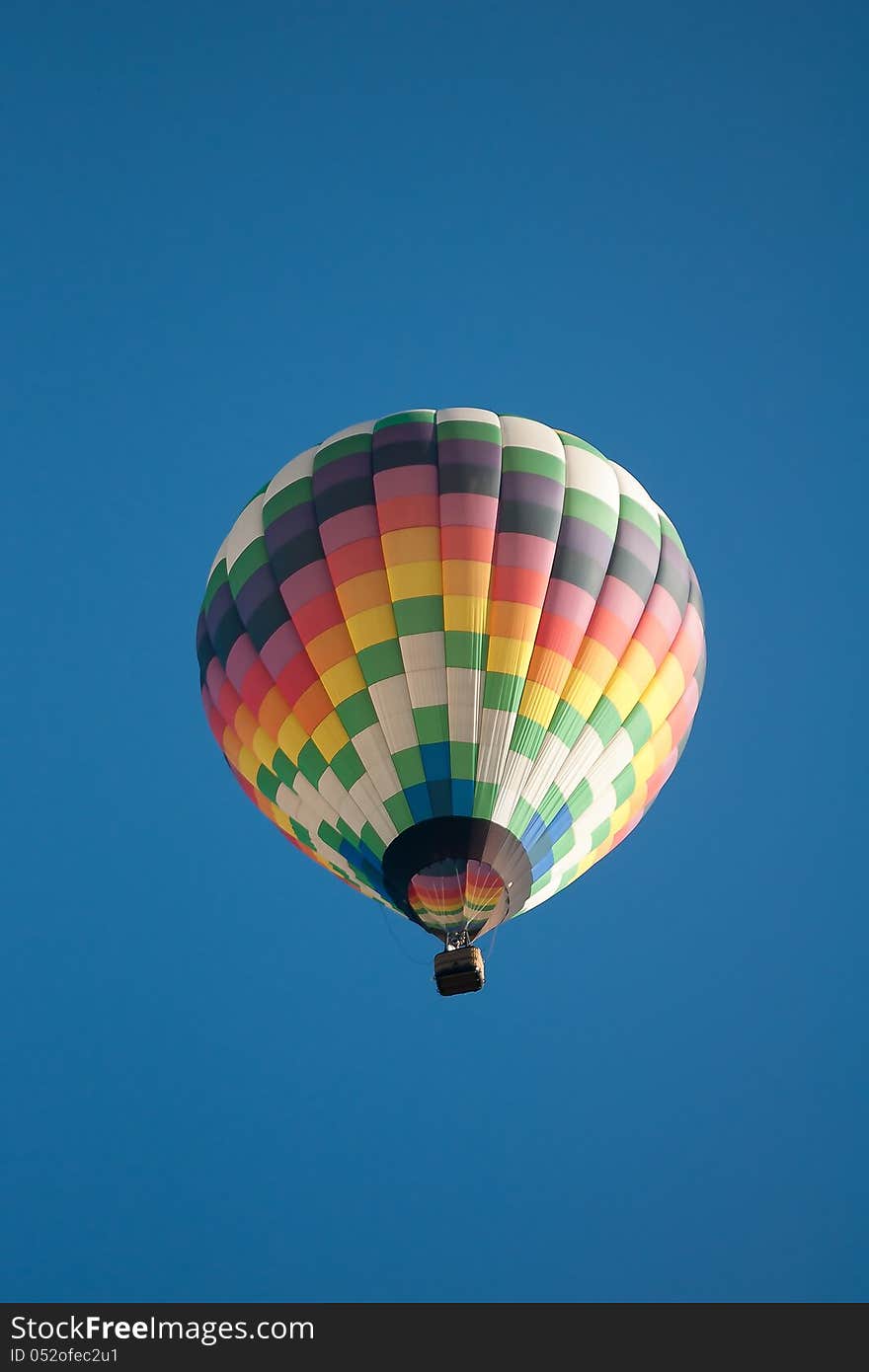 Hot air balloon over farm land with blue sky