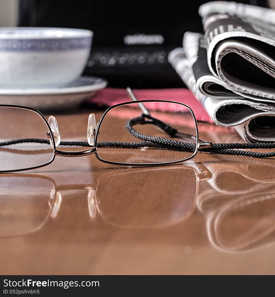 Pile of newspaper & glasses on table