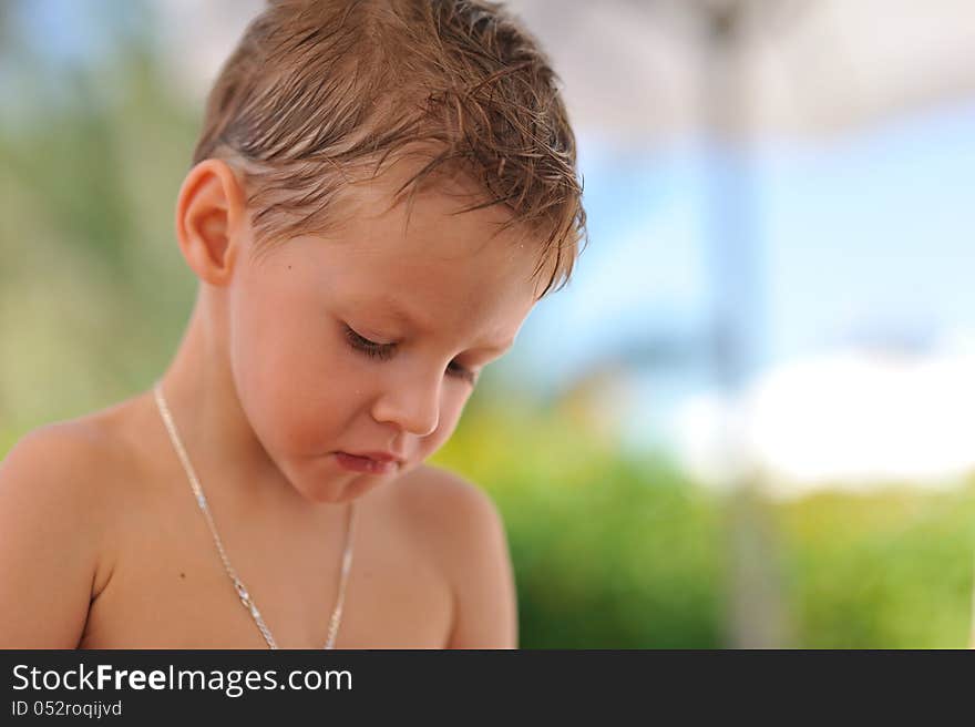 Close up the person of the sad boy with wet hair on the nature. Close up the person of the sad boy with wet hair on the nature