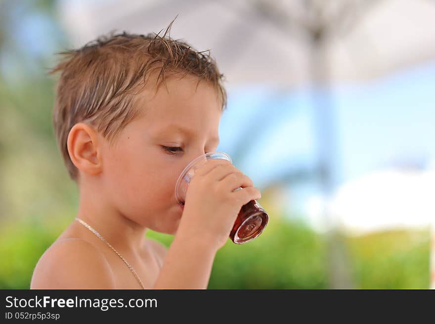 Close up the boy drinks in a heat from a glass juice. Close up the boy drinks in a heat from a glass juice