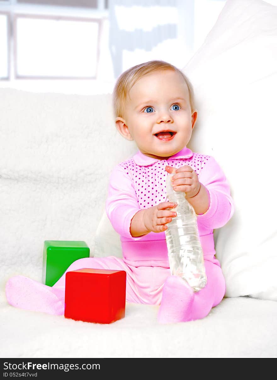 Portrait of a cheerful little girl drinking water from a bottle on the abstract background