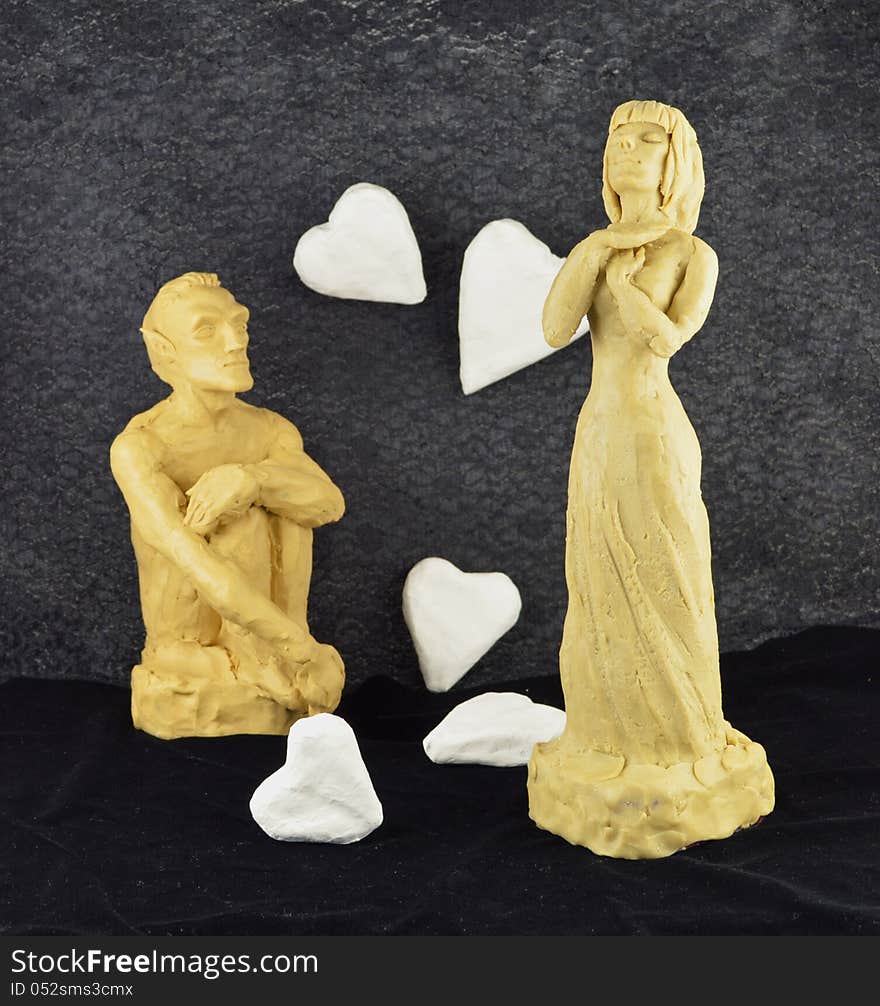 Man and woman made of clay with white paper hearts. Man and woman made of clay with white paper hearts