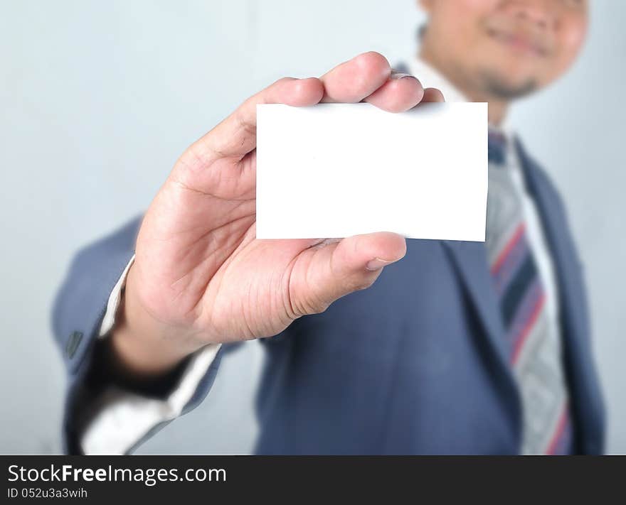 Business man show blank card in front of grey background