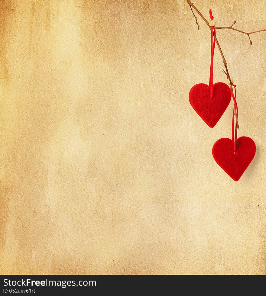 Two red hearts, hanging on a branch over the paper background. Two red hearts, hanging on a branch over the paper background.