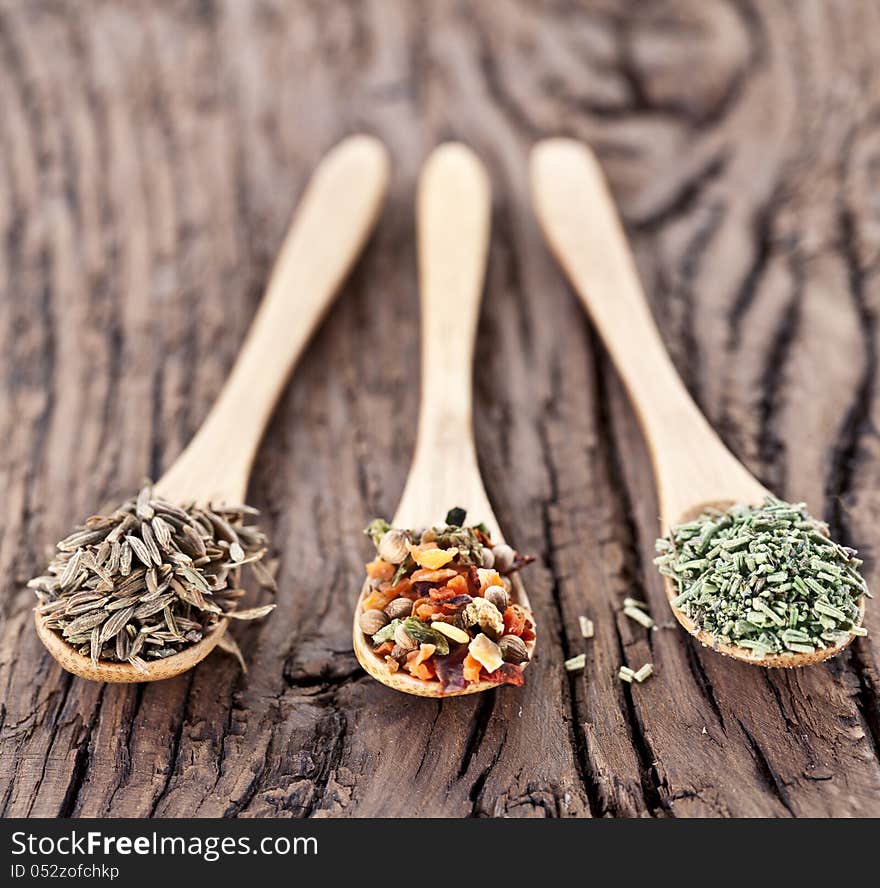 Variety of spices in the spoons on an old wooden table. Variety of spices in the spoons on an old wooden table.