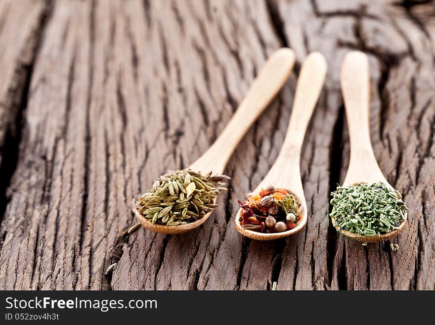 Variety of spices in the spoons on an old wooden table. Variety of spices in the spoons on an old wooden table.