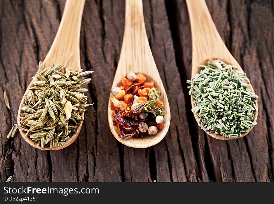 Variety of spices in the spoons on an old wooden table. Variety of spices in the spoons on an old wooden table.