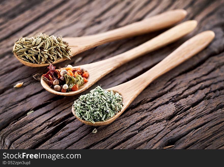 Variety of spices in the spoons on an old wooden table. Variety of spices in the spoons on an old wooden table.