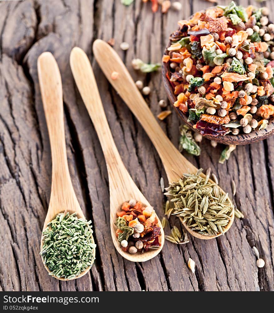 Variety of spices in the spoons on an old wooden table. Variety of spices in the spoons on an old wooden table.