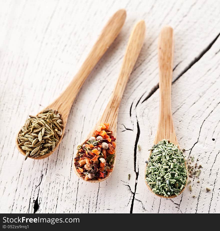 Variety of spices in the spoons on an white old wooden table. Variety of spices in the spoons on an white old wooden table.