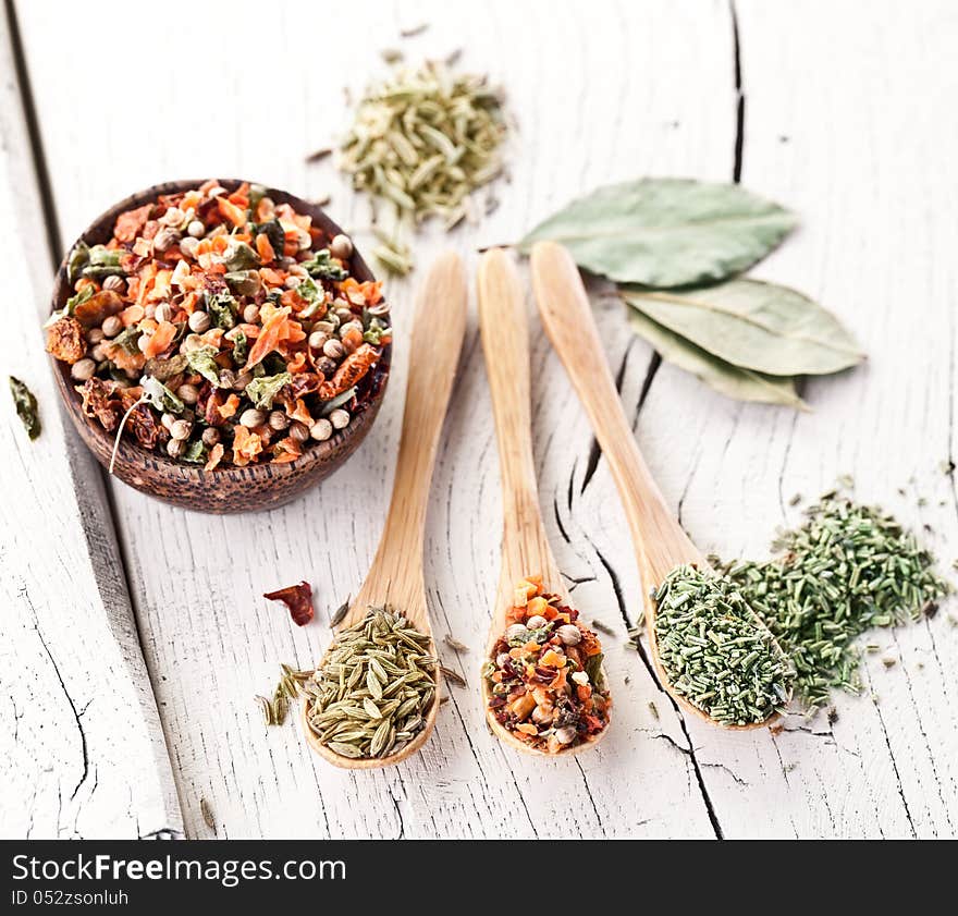 Variety of spices in the spoons on an white old wooden table. Variety of spices in the spoons on an white old wooden table.