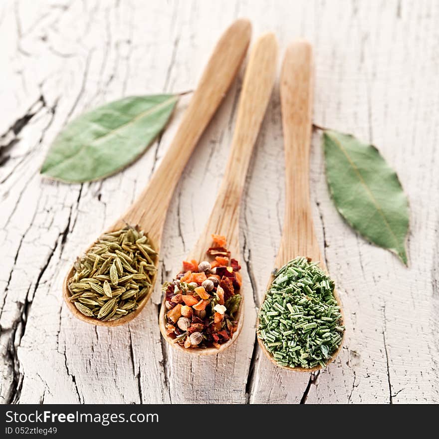 Variety of spices in the spoons on an white old wooden table. Variety of spices in the spoons on an white old wooden table.