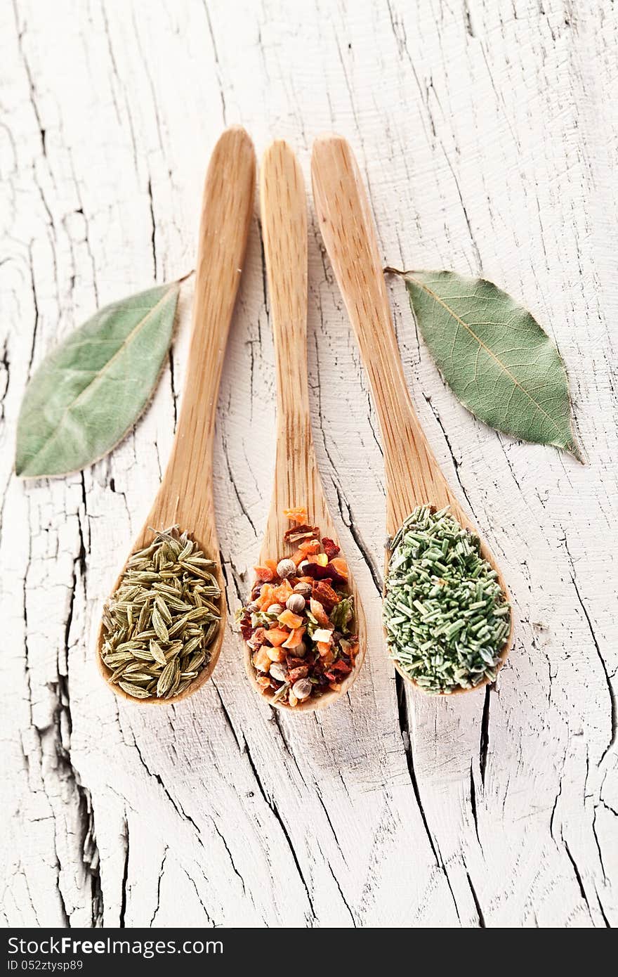 Variety of spices in the spoons on an white old wooden table. Variety of spices in the spoons on an white old wooden table.