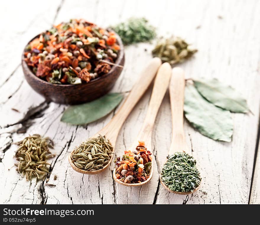 Variety of spices in the spoons on an white old wooden table. Variety of spices in the spoons on an white old wooden table.