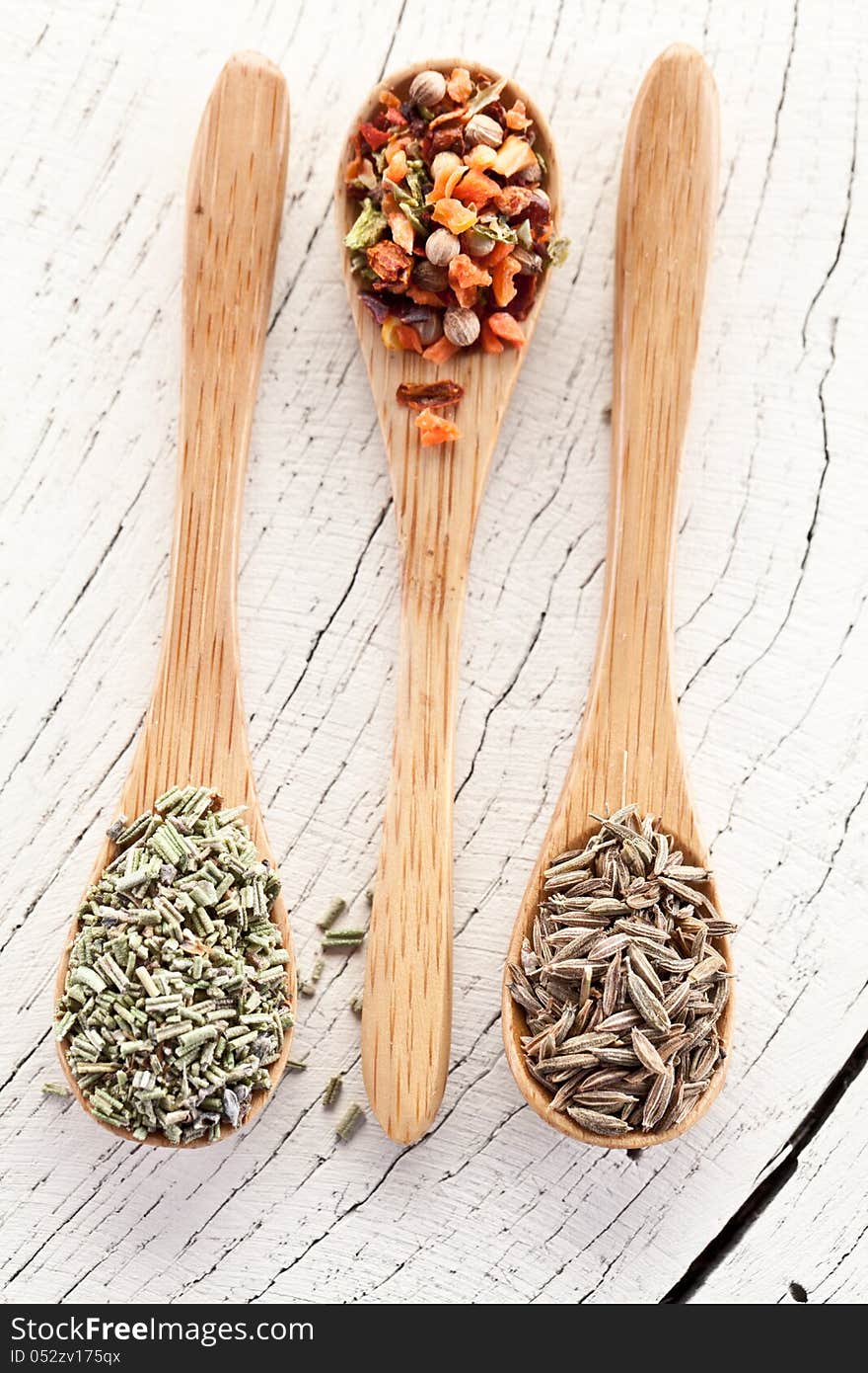 Variety of spices in the spoons on an white old wooden table. Variety of spices in the spoons on an white old wooden table.