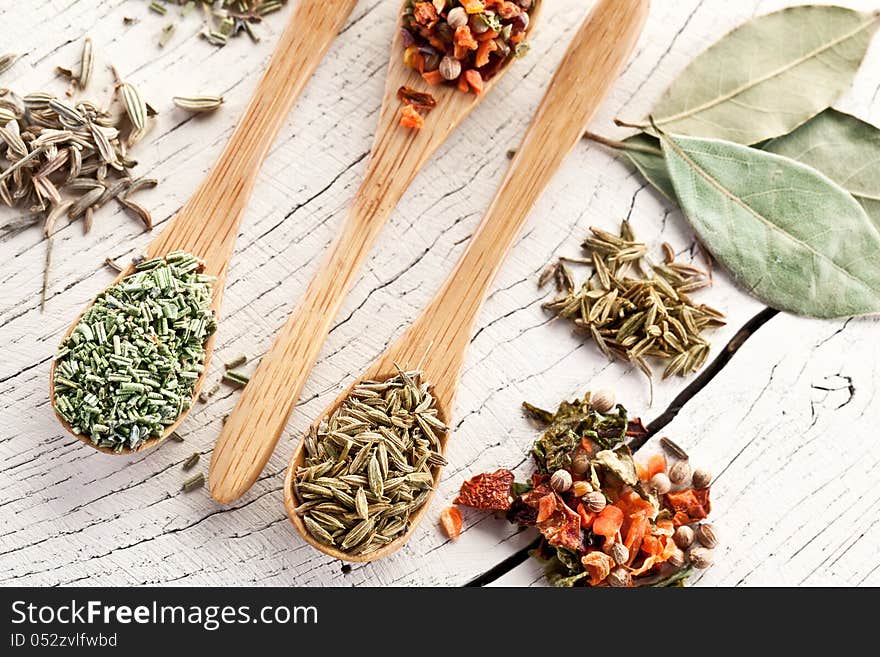 Variety of spices in the spoons on an white old wooden table. Variety of spices in the spoons on an white old wooden table.