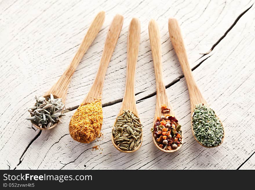 Variety of spices in the spoons on an white old wooden table. Variety of spices in the spoons on an white old wooden table.