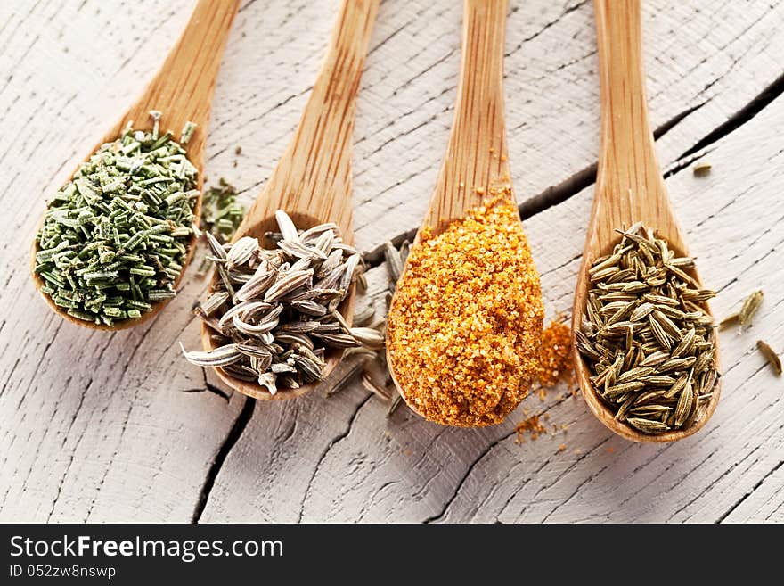 Variety of spices in the spoons on an white old wooden table. Variety of spices in the spoons on an white old wooden table.