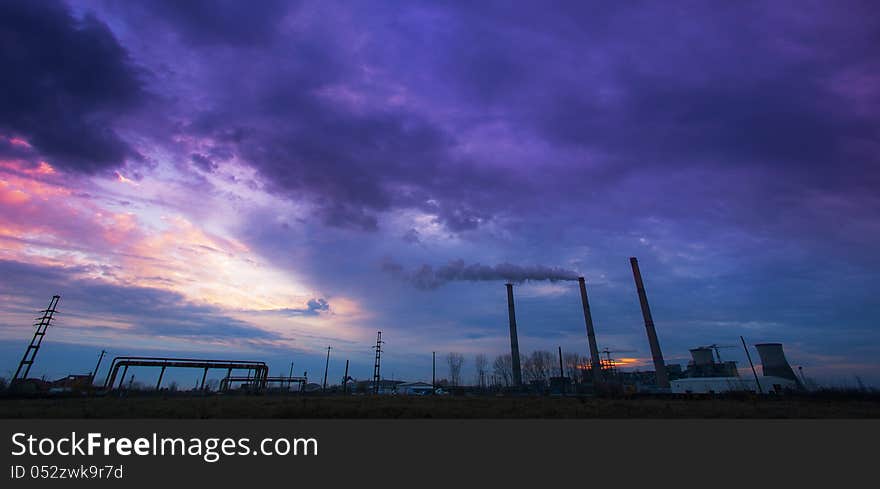 Coal powered plant and smoke stacks under dramatic evening sky