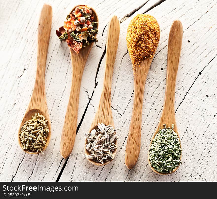 Variety of spices in the spoons on an white old wooden table. Variety of spices in the spoons on an white old wooden table.