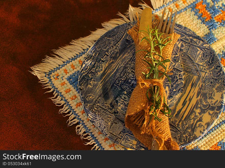 Old-fashioned silverware and plate on rustic setting place. Sepia tone. Old-fashioned silverware and plate on rustic setting place. Sepia tone.