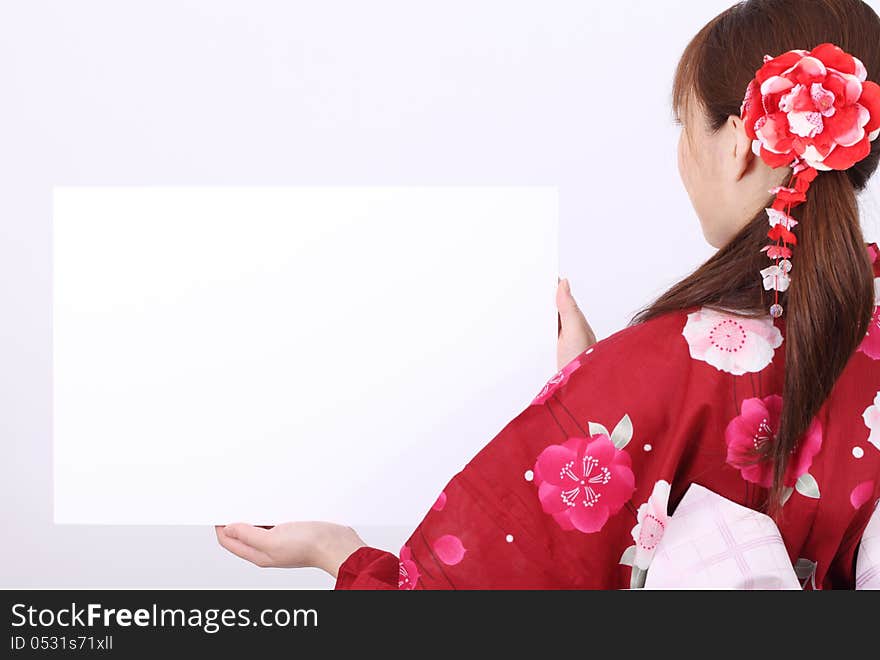 Rear view of young asian woman in traditional clothes of kimono holding a blank board