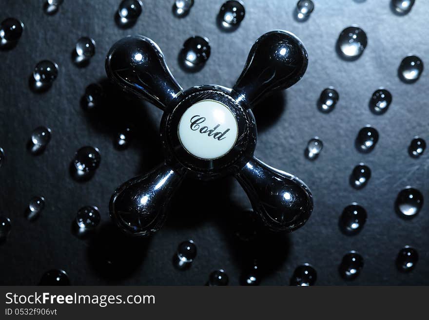 Old faucet on dark background with drops of water