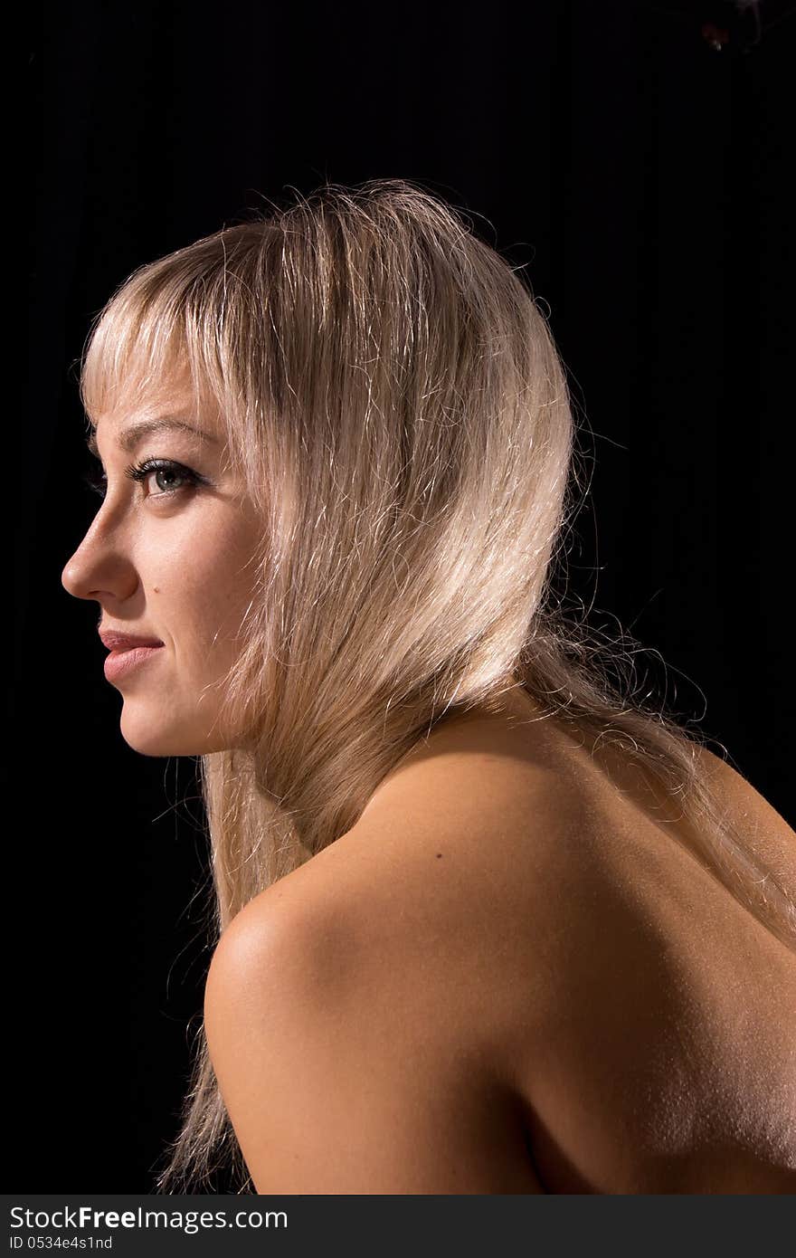 Portrait of blonde girl on a dark background.