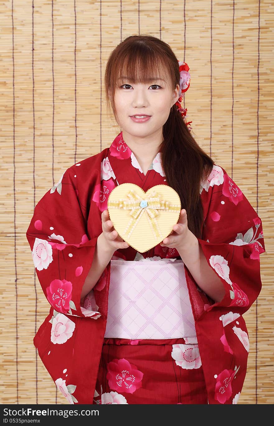 Young asian woman in traditional clothes of kimono, holding a gift box. Young asian woman in traditional clothes of kimono, holding a gift box