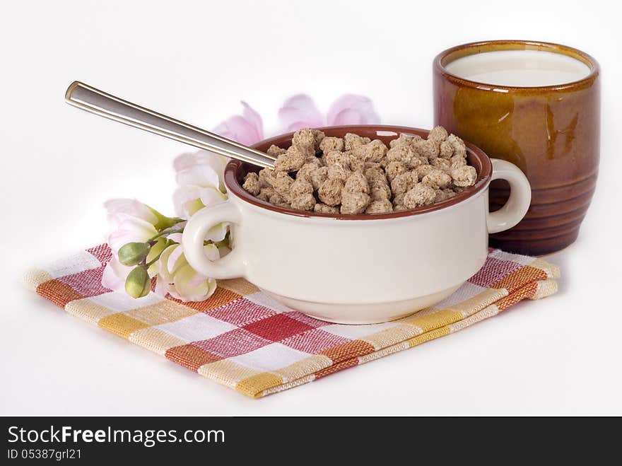 Cereal flakes in ceramic bowl and a milk in a ceramic cup on a flax napkin. Cereal flakes in ceramic bowl and a milk in a ceramic cup on a flax napkin