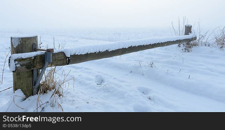 Wooden barrier over snowy road with dense fog in background. Wooden barrier over snowy road with dense fog in background