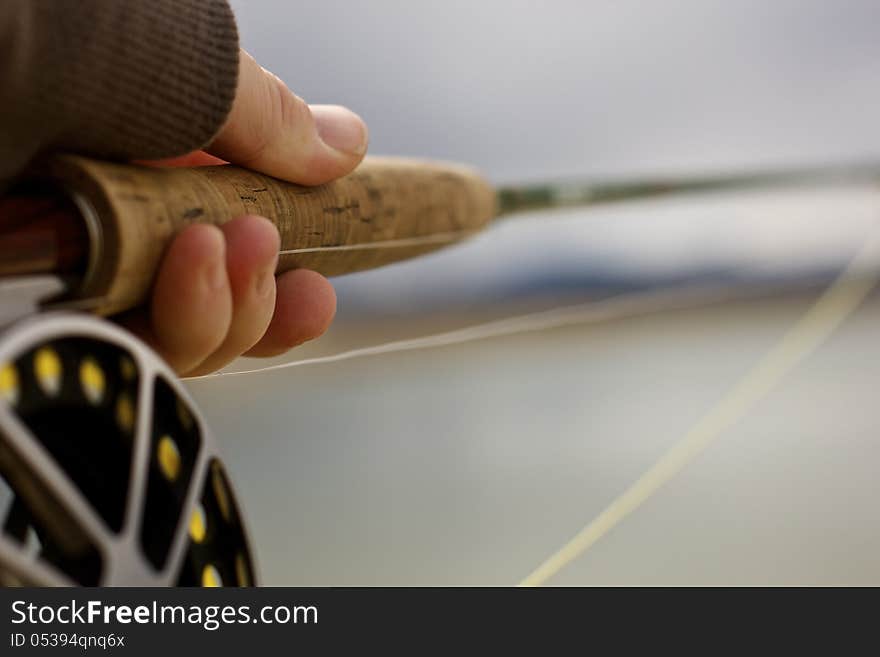 A man holding onto a fly rod and reel. A man holding onto a fly rod and reel.