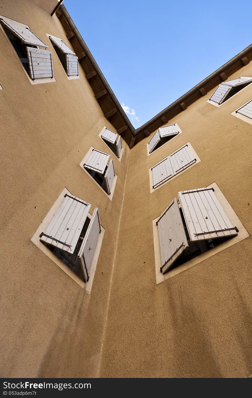 Two orange plastered walls in an angle covered with partially closed shutters, shot from a low angle. Two orange plastered walls in an angle covered with partially closed shutters, shot from a low angle.