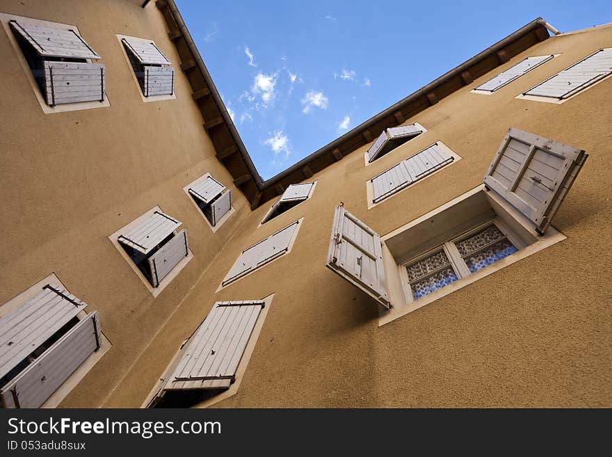 Two orange plastered walls in an angle covered with partially closed shutters, shot from a low angle. Two orange plastered walls in an angle covered with partially closed shutters, shot from a low angle.