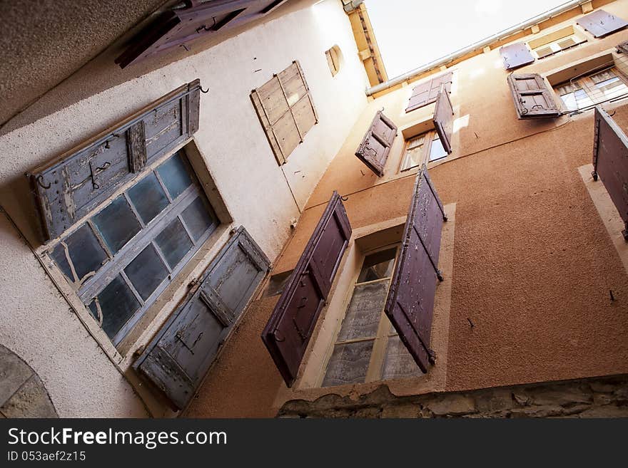 Orange plastered walls in an alley covered with shutters, shot from a low angle. Taken in the French city of Millau. Orange plastered walls in an alley covered with shutters, shot from a low angle. Taken in the French city of Millau