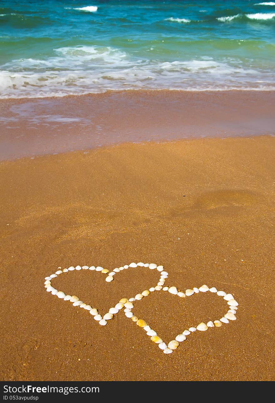 Connected hearts made from hells on beach - love concept. Connected hearts made from hells on beach - love concept