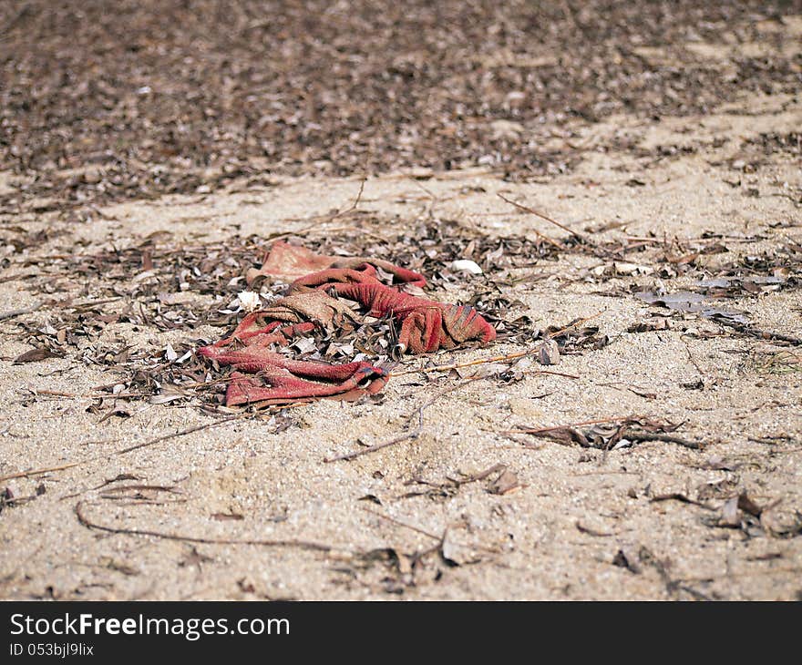 An old red rag on a sandy beach. An old red rag on a sandy beach