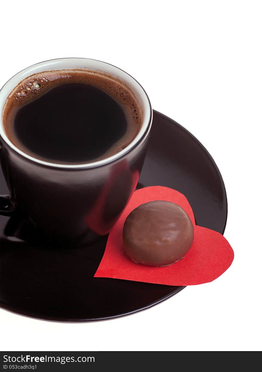 Round chocolate candy in the heart of red paper and black coffee on a white background. Round chocolate candy in the heart of red paper and black coffee on a white background