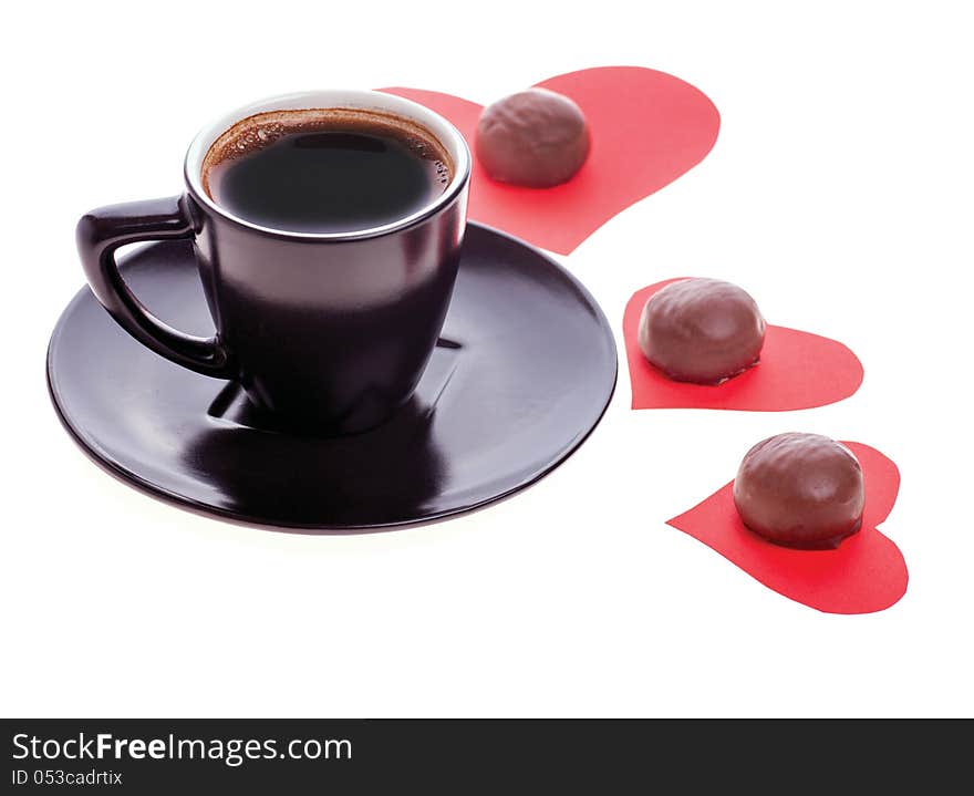 Round chocolate candy in the heart of red paper and black coffee on a white background. Round chocolate candy in the heart of red paper and black coffee on a white background