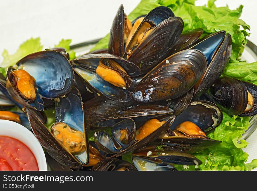 This is a plate of steamed mussels with lettuce leaves on a plate