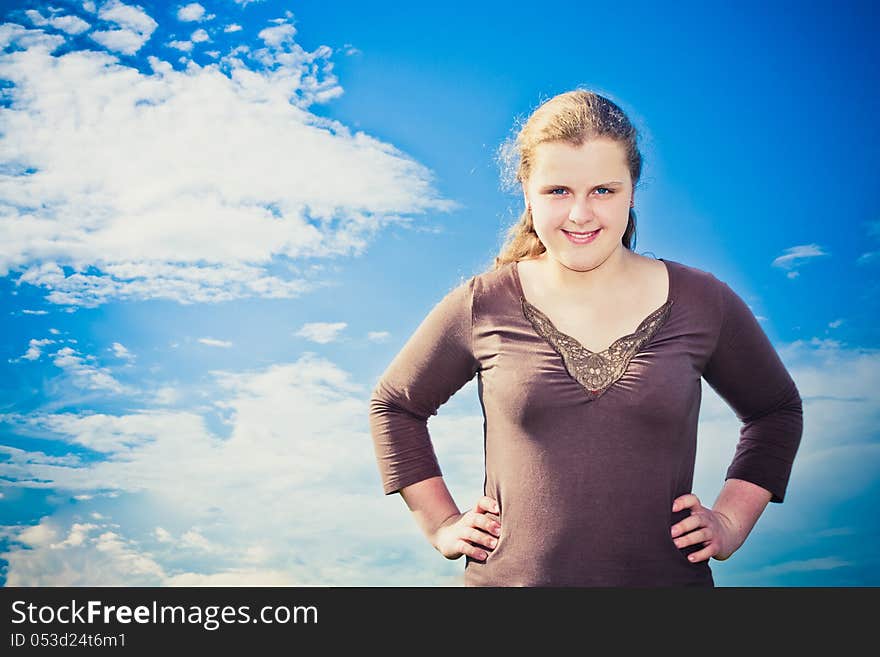 Smiling Girl With Arms Holds On A Waist On Sunny Day Under Blue Sky And Clouds. Smiling Girl With Arms Holds On A Waist On Sunny Day Under Blue Sky And Clouds