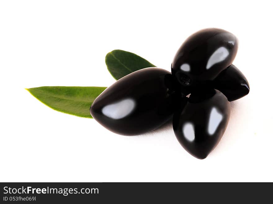 Four shiny black olives with leaves on white background. Four shiny black olives with leaves on white background