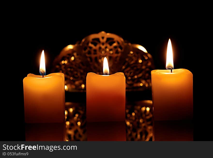 Three lit candles on a black background