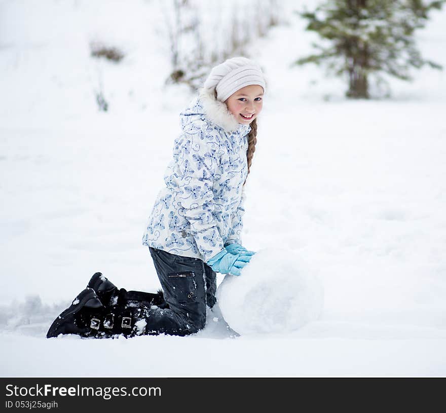 Child Making Snowman In Winter Park