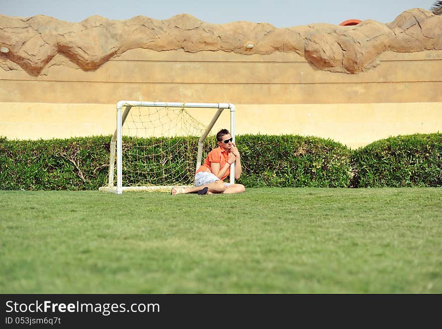 On a green grassy field in collars the guy in sun glasses sits. On a green grassy field in collars the guy in sun glasses sits